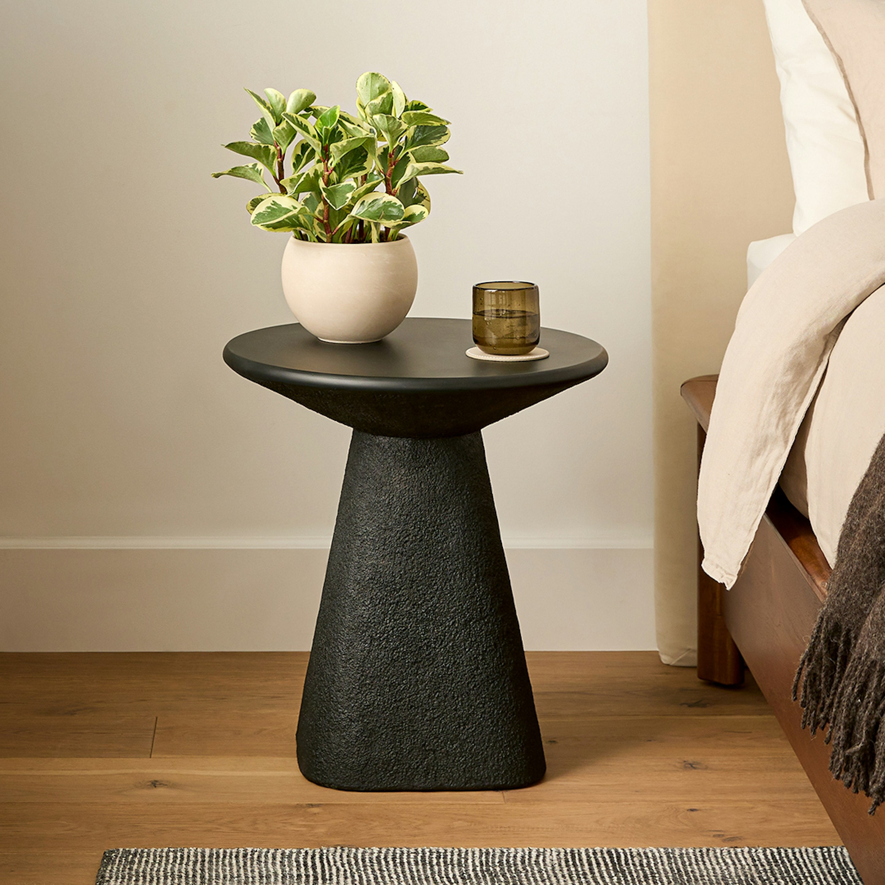 Table d'appoint minimaliste en béton noir, dessus lisse et courbes douces pour le salon