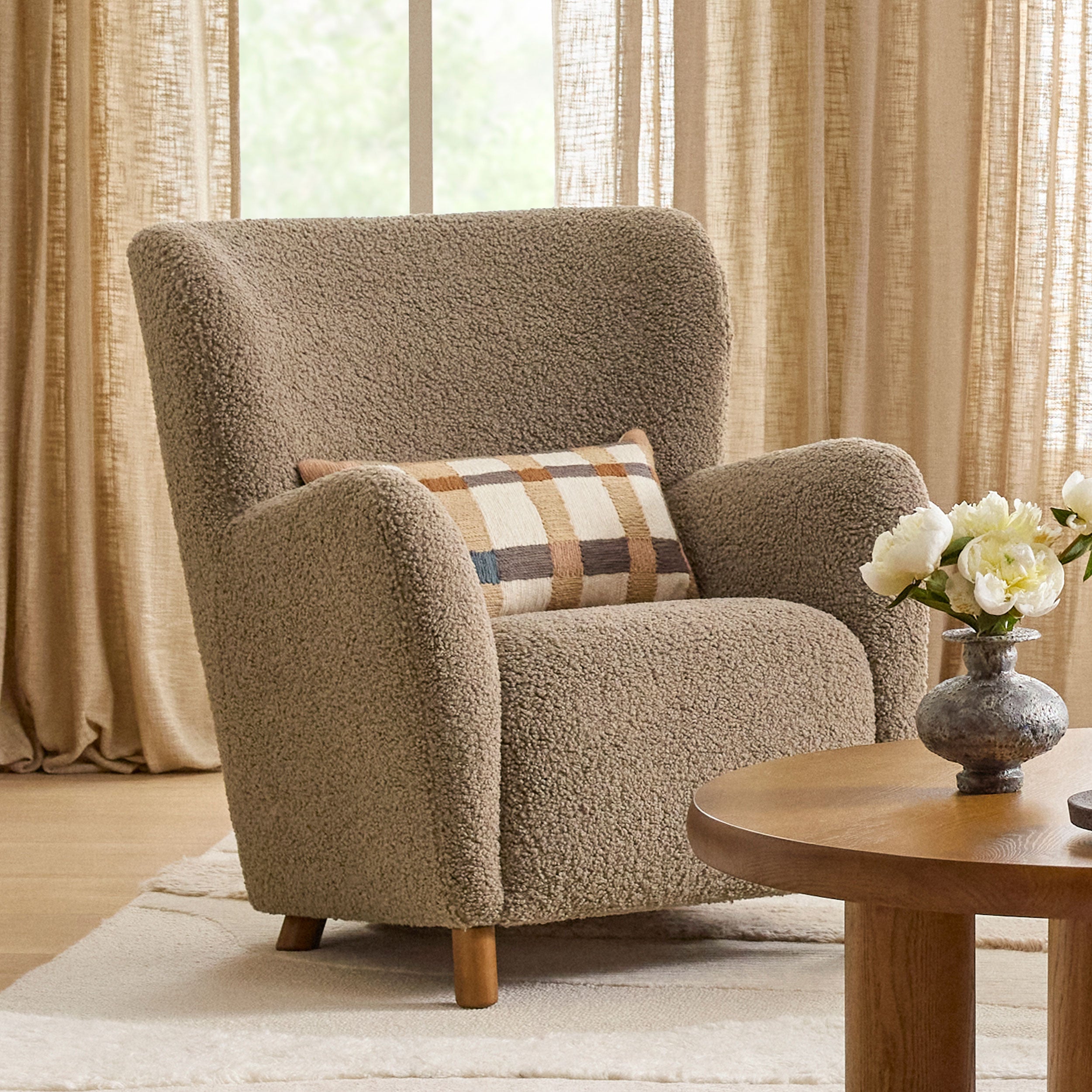 Fauteuil de salon contemporain en tissu bouclé taupe, avec dossier haut et assise profonde, pour salon